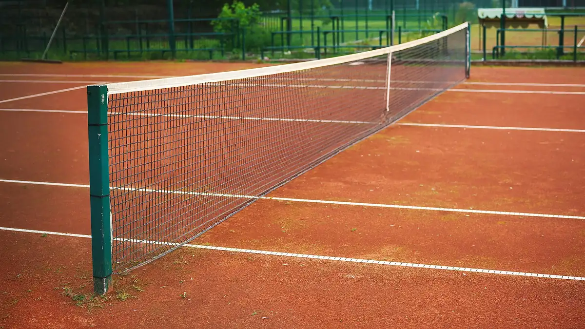 Tennis net across a clay court